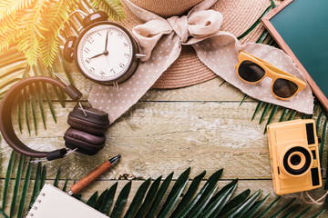 Fototapeta na wymiar summer vacation travel frame border background with travel stuff camera notebook glasses and woman hat flatlay image on old rustic wood table top background with free copy space