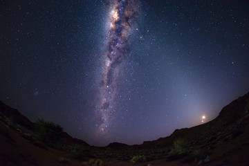 Starry sky and Milky Way arch with moon in the Namib desert in Namibia, Africa. The Small Magellanic Cloud on the left hand side.