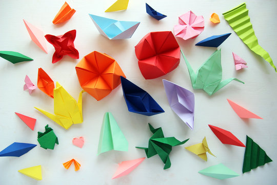 Man doing origami. Multicolored Origami and paper on  a white table.