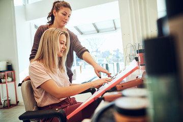 Smiling client and hairdresser choosing hair colors in a salon