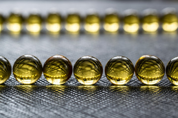 Fish fat round pills on black gray background, medicine capsule contains omega 3 vitamin