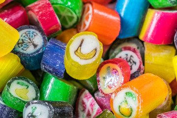Fototapeta na wymiar Colorful candy sweets close up, selective focus. Different tastes and drawings of fruits on candies, banana taste in front, made in prague