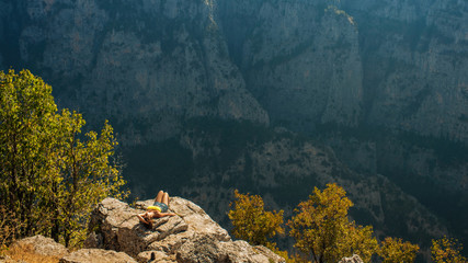 A girl on the peak of mountain opposite the gorge of Vikos in Greece. Vikos gorge in Greece in zagoria. Epirus