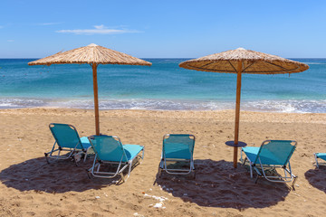 Sunbeds with umbrellas on beautiful sandy Paleochori beach on Milos island. Cyclades, Greece.