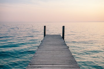 Obraz premium View of a wooden pier on the seashore with clear morning sky and sea with turquoise water.