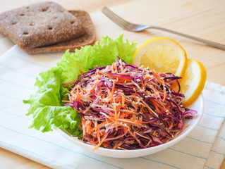 Fresh salad plate with mixed roots (celery, carrot, red cabbage) on light wooden background close up. Healthy food. Green meal.
