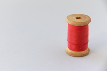 Fototapeta na wymiar wooden coil with red thread. selective focus