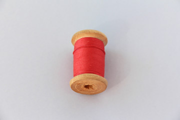 Fototapeta na wymiar wooden coil with red thread. selective focus