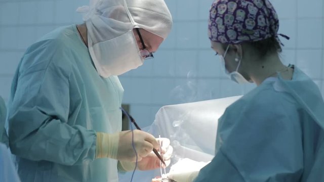 Surgeon in the operating room cauterizes the wound to the patient