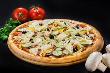 Vegetarian delicious Greek pizza with mozzarella and feta cheeses, tomatoes, pepper and cucumbers on wooden board on dark background