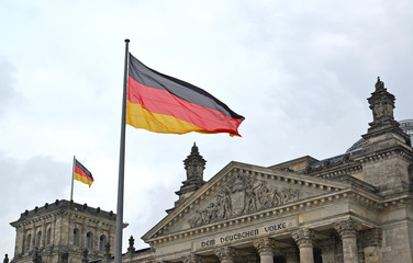 Naklejka premium National flag of Germany flutters against the background of the Reichstag building. Berlin, Germany