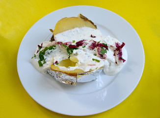 Potatoes baked in a foil with sauce and greens