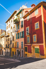Old traditional houses in different bright colors along narrow street in old town of Nice, Cote d'Azur, France