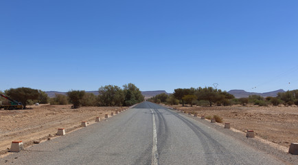 Fototapeta na wymiar moroccan rocky desert landscape with plants and mountain range, assa-zag, Road in the desert