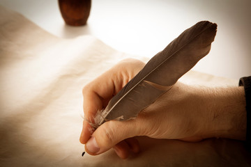 writer holds a fountain pen over writing paper and a signature