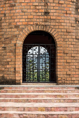 Portrait of old brick building with iron gate. They are built in ancient style.