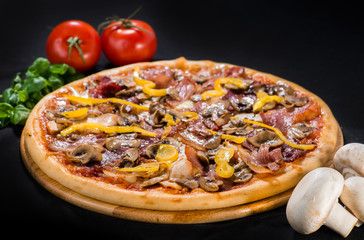 Appetizing pizza with salami, mozzarella, pepper, olives and pickled cucumbers on wooden board on dark background