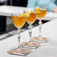 Line of three glasses with orange cocktail on bar counter, selective focus