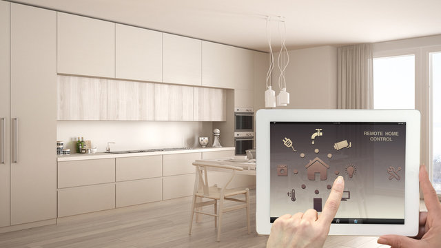 Smart remote home control system on a digital tablet. Device with app icons. Interior of classic white and wooden kitchen in the background, architecture design