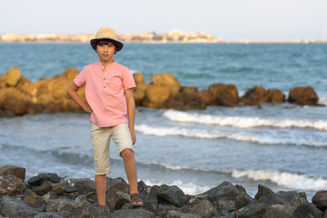 The boy is standing by the sea.