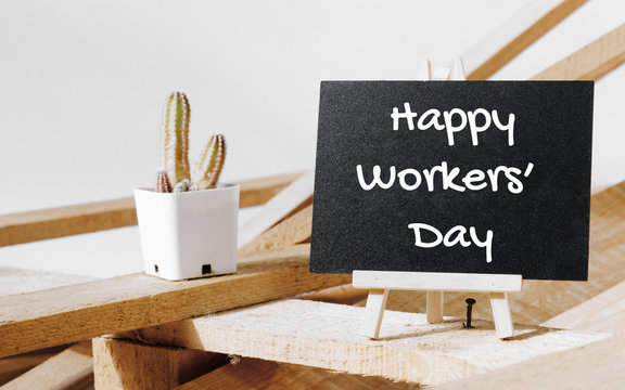 Happy International Workers' day and Happy Labor day concept. Small chalk board with text Happy Worker's Day with cactus and wooden pallet background on white background.
