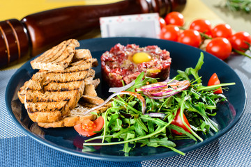 Dish with beef tartare, tomatoes and leaves in a restaurant