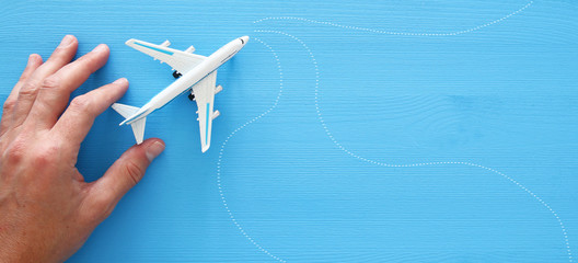 top view photo of man's hand holding toy airplane over blue wooden background.