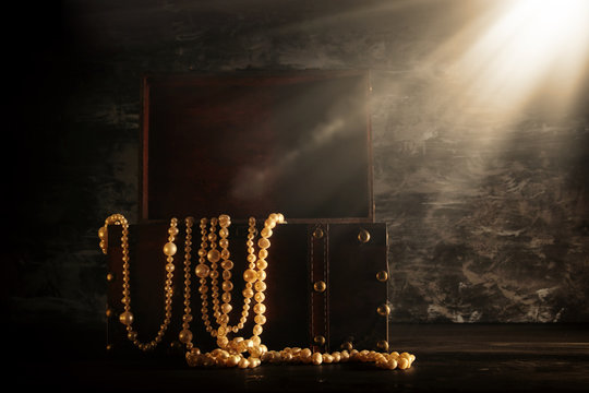 Image of mysterious opened old wooden treasure chest with light. An adventure and fantasy medieval period. Selective focus.
