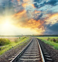 Fotobehang Treinspoor spoorlijn naar horizon in gekleurde zonsondergang