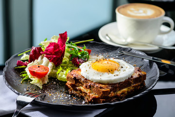 Dish with toast with fried eggs and salad with tomatoes and lettuce leaves at the cafe