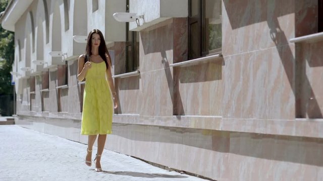 Attractive elegant young woman looking around and walking on the summer street. Slow motion. HD
