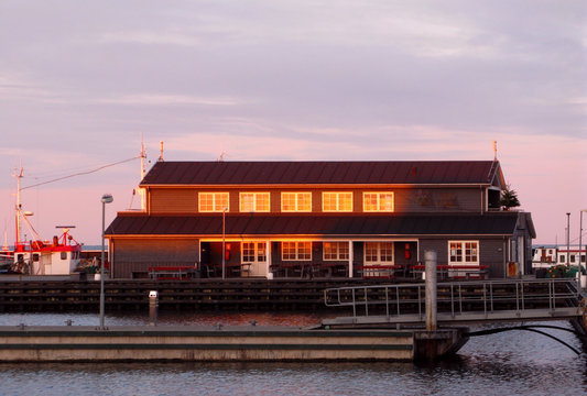 Laesoe / Denmark: The golden wintry twilight reflects in the windows of the public service building in the empty marina in Vesteroe Havn