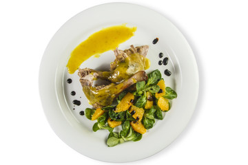 Duck legs with orange sauce and lamb's lettuce salad with oranges and vinegaron white plate isolated on white.