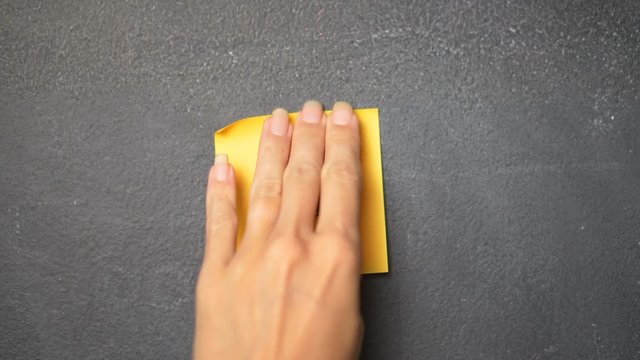 Closeup woman's hand sticking note with letter "G" on the blackboard - video in slow motion