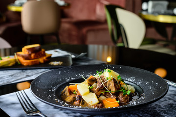 Juicy duck fillet with potatoes and mushrooms in a plate in the cafe, selective focus