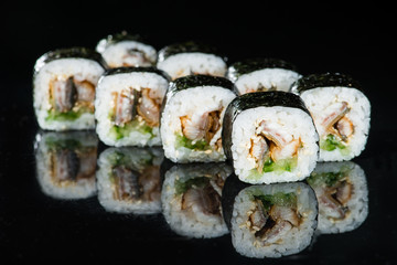 Japanese cuisine. Appetizing maki sushi rolls with rice, avocado, cucumber and shrimp on dark background