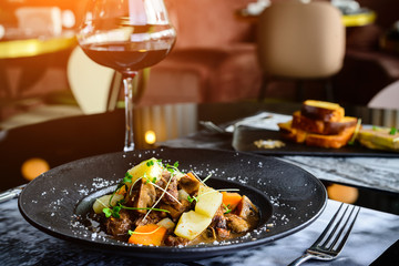 Juicy duck fillet with potatoes and mushrooms in a plate in restaurant in rays of the sun