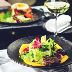 Tasty dish with juicy beef steak and fresh lettuce leaves at a restaurant, toned image