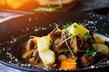 Juicy duck fillet with potatoes and mushrooms in a plate in restaurant in rays of the sun, close-up