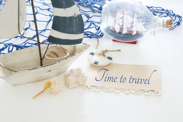 nautical concept image with white decorative sail boat, seashells and note over white wooden table.