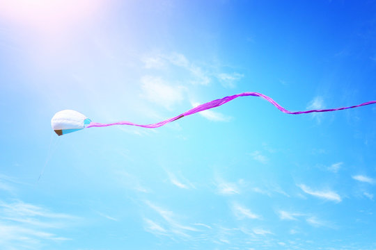 Colorful kite flying in the blue sky through the clouds.