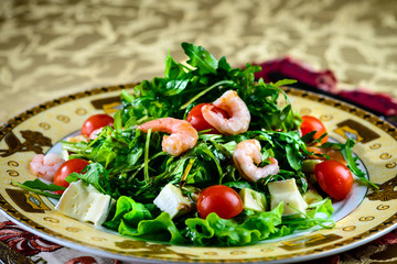 Salad with shrimps, lettuce leaves and tomatoes in a plate in a restaurant