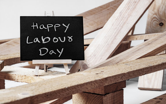 Happy International Workers' day and Happy Labor day concept. Small chalk board with text Happy Labour Day with wooden pallet background on white background.