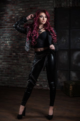 Fototapeta na wymiar redhead adult girl biker in the leather wear indoor
