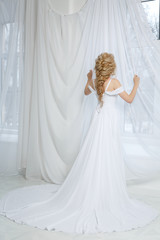 Невеста стоит у окна в белом платье