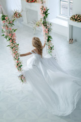 Девушка в свадебном платье на качелях