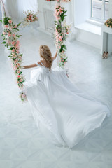 Девушка в свадебном платье на качелях