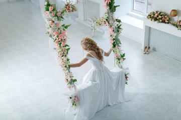 Девушка в свадебном платье на качелях