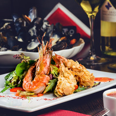 Romantic dinner at a restaurant. Delicious prepared shrimp with tomatoes, sauce and basil leaves, toned image