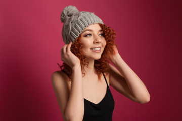 Cute young woman wearing warm winter hat posing in studio